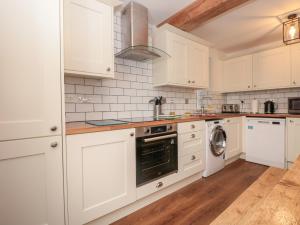 eine Küche mit weißen Schränken und einer Waschmaschine und einem Trockner in der Unterkunft Grants Cottage in Dartmouth