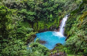 a waterfall in a forest with a blue pool of water at Casita Don Eliber in Fortuna