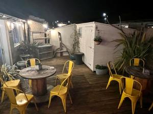 un patio con sillas y mesas amarillas, una mesa y sillas en ByTheSea Guest House en Ayr