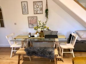 uma sala de jantar com uma mesa de vidro e cadeiras brancas em 3 York Mews em Bath