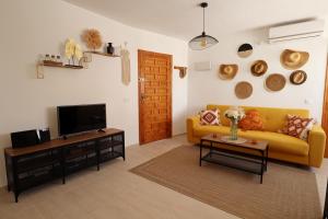 een woonkamer met een gele bank en een tv bij Oleza Sun Playa Flamenca in Playa Flamenca