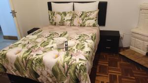 una camera da letto con un letto con copriletto floreale di Bertha's Place a Pretoria