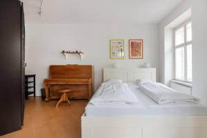 a white bedroom with a bed and a piano at Studententraum am Naschmarkt in Vienna