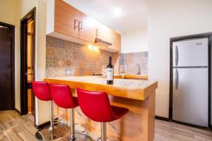 a kitchen with a bar with red chairs and a refrigerator at BLAZE Hotel & Suites Puerto Vallarta in Puerto Vallarta