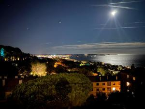 uma vista de uma cidade à noite com a lua em Appartement CANNES, vue mer triples exposition em Cannes