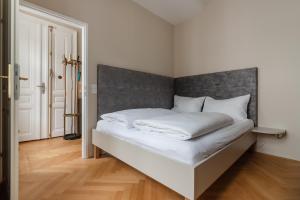 ein Schlafzimmer mit einem weißen Bett mit einem grauen Kopfteil in der Unterkunft Hochwertiges Apartment mit direkter Anbindung zum Zentrum in hippen Viertel in Wien