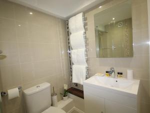 a bathroom with a toilet and a sink and a mirror at Harpenden House in Harpenden