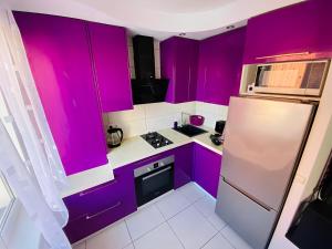a kitchen with purple cabinets and a refrigerator at Coastal Comfort Apartments in Liepāja