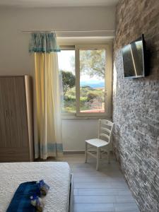 a bedroom with a bed and a chair and a window at B&B Isola Mia in La Maddalena