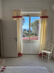 una camera da letto con una porta, una sedia e una finestra di B&B Isola Mia a La Maddalena