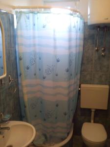 a bathroom with a shower curtain with a toilet and a sink at Guesthouse Marija in Cavtat