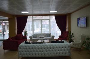 a living room with a large white couch and red chairs at Quars Garden Hotel in Koçyazı