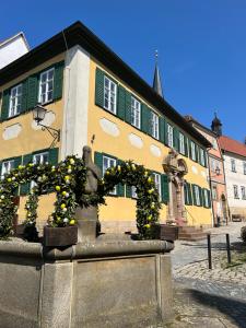 Seßlach的住宿－M96 Ferienwohnung，一座黄色和绿色的建筑,前面有雕像