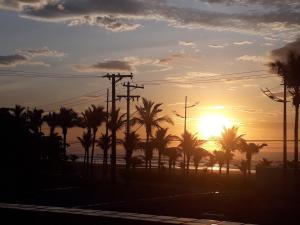 a sunset with palm trees and power lines at Pousada dos Eletricitarios in Praia Grande