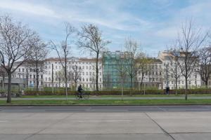 une personne faisant du vélo devant un grand bâtiment dans l'établissement Klein, aber fein in zentraler Ruhelage, à Vienne