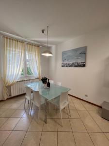 comedor con mesa de cristal y sillas blancas en Villa Azzuro Blue, en Lignano Sabbiadoro