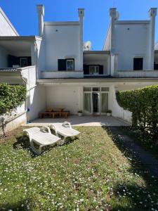 un grande edificio bianco con due tavoli da picnic nel cortile di Villa Azzuro Blue a Lignano Sabbiadoro