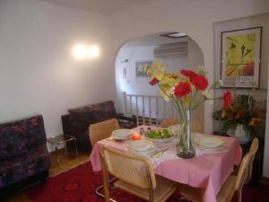 ein Esszimmer mit einem rosa Tisch und einer Blumenvase in der Unterkunft Calle Burchio in Grado