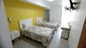 a bedroom with two beds and a yellow wall at Hotel Santa Maria in Ica