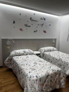 two beds in a bedroom with butterflies on the wall at El sitio de mi recreo Ávila in Ávila