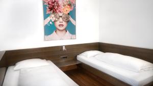 2 Betten in einem Zimmer mit einem Bild einer Frau in der Unterkunft Stadthotel Heilbronn in Heilbronn