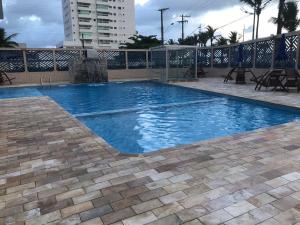 a swimming pool with blue water in a building at Pousada dos Eletricitarios in Praia Grande