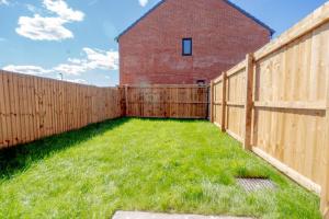a backyard with a wooden fence and grass at Stunning canal view 2 bedroom home with free parking in Manchester