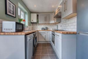 uma cozinha com armários brancos e um micro-ondas em CAPRI 13 SA - Contemporary 2 bedroom house in Loughborough with free parking, Close to Loughborough University & M1 Motorway em Loughborough