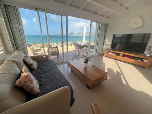 a living room with a couch and a view of the ocean at Sweet Home SXM Baie Nettlé Pieds dans l'eau in Saint Martin