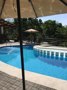 duży basen z parasolem i krzesłami w obiekcie Casa de playa con piscina y jacuzzi privado w mieście Puntarenas
