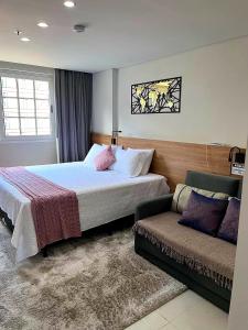 um quarto de hotel com uma cama e um sofá em Flat 217 Granja Brasil - Com Piscina Aquecida Em Itaipava em Itaipava