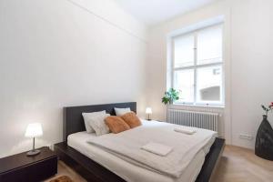 una camera da letto con un grande letto con lenzuola bianche e una finestra di Old Town Square Luxury Apartment a Praga