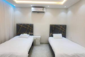 Habitación con 2 camas y TV en la pared. en راحتك - إقامة وفخامة en Makkah