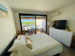 - une chambre avec un lit, une télévision et un balcon dans l'établissement Studio à 350m de la plage, terrasse ouverte, clim, au Grau-du-Roi