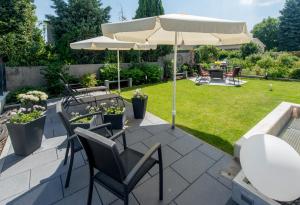 eine Terrasse mit einem Tisch, Stühlen und einem Sonnenschirm in der Unterkunft Premium-Apartment Lifestyle 1b bei Fam Horster in Bensheim