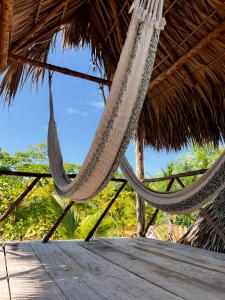 a pair of hammocks hanging from a straw hut at Macarena Paredon in El Paredón Buena Vista