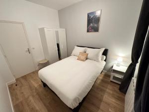 um pequeno quarto com uma cama com lençóis brancos em Appartement à 15min de paris em Drancy