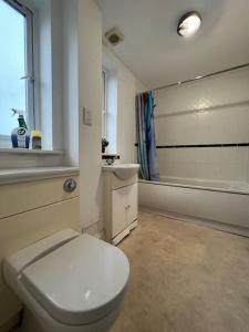 a bathroom with a white toilet and a sink at New build 2 bed flat, London in London