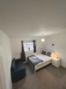 a bedroom with a bed and a couch and a chair at New build 2 bed flat, London in London