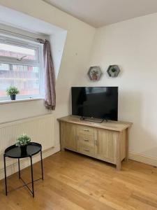 a living room with a flat screen tv and a table at New build 2 bed flat, London in London