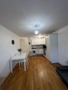a living room with a white table and a kitchen at New build 2 bed flat, London in London
