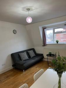 a living room with a black couch and a table at New build 2 bed flat, London in London