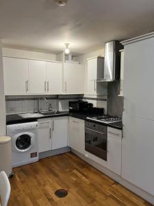 a kitchen with white cabinets and a stove top oven at New build 2 bed flat, London in London
