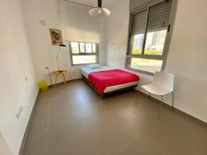 a bedroom with a red bed and a white chair at Herzliya Luxury On The Park in Herzliya