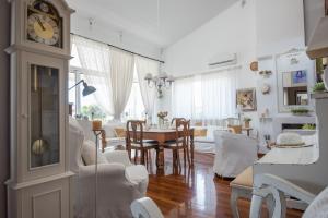 uma sala de estar com um relógio, uma mesa e cadeiras em Unique house by the sea em Paralía Proastíou