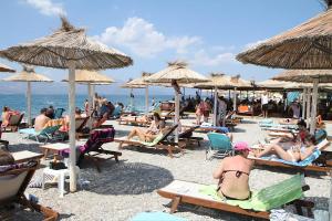 a group of people sitting on the beach under umbrellas at Bright apartment in Nea Palatia • Oropos in Néa Palátia