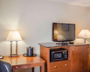 a tv sitting on top of a wooden dresser with a desk at Hotel Hanna in Harrisburg