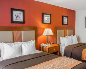 2 bedden in een hotelkamer met oranje muren bij Quality Inn Riverfront in Harrisburg