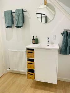 La salle de bains est pourvue d'un lavabo blanc et d'un miroir. dans l'établissement Lejlighed i naturskønt område, à Silkeborg