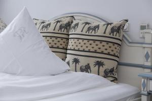 a bed with white sheets and pillows with palm trees at Hotel Zum Alten Brunnen in Rheine